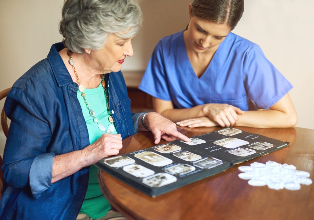 Shes got plenty of photos to share. Shot of a resident and a nurse looking through a photo album